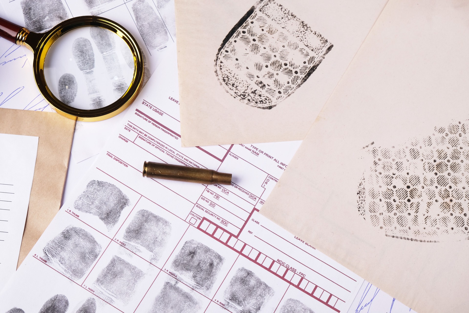 Forensic concept, evidence set on table, judge gavel, fictitious signature samples, spent cartridge case, shoe marks and fingerprints, top view